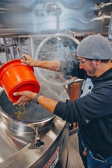 Mikey&rsquo;s Late Night Slice employee adds hops to the whirlpool vessel.