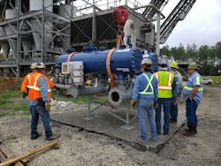 Workers setting a filter skid assembly on a new concrete pad. Workers setting a filter skid assembly on a new concrete pad.