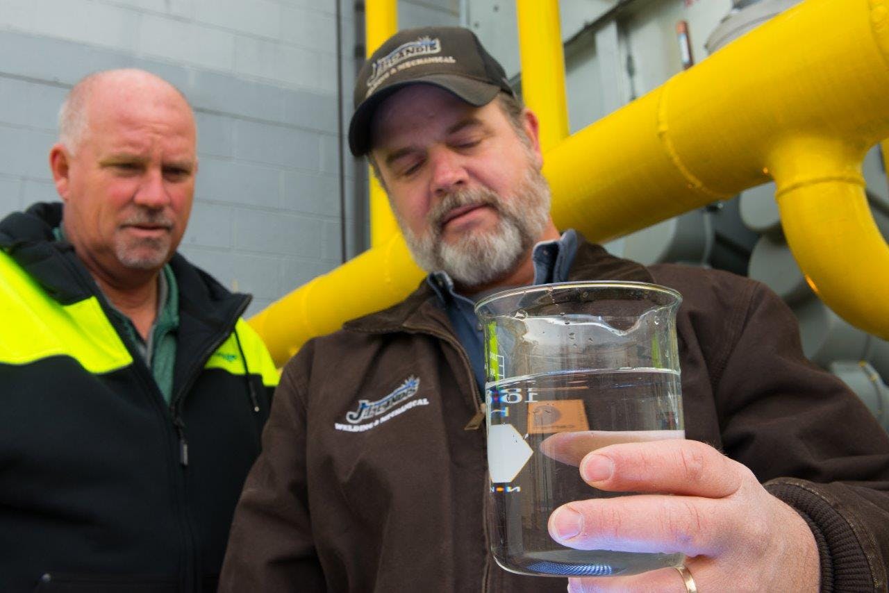 Technicians examine a clean water sample taken from an industrial cooling tower.