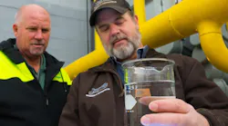 Technicians examine a clean water sample taken from an industrial cooling tower.