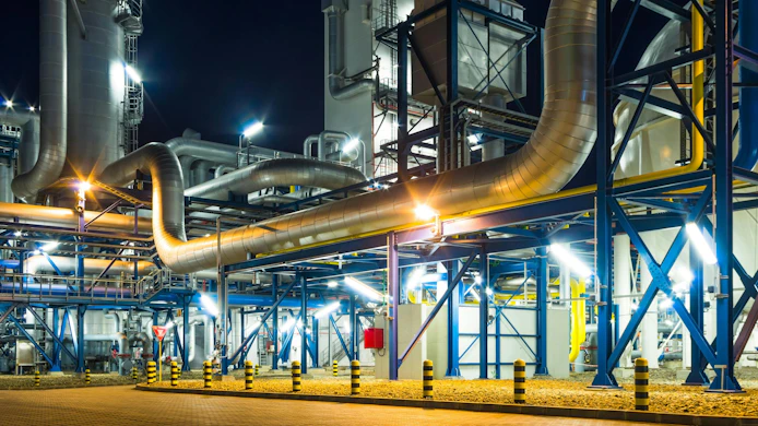 Pumps and piping system inside of industrial plant at night
