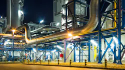 Pumps and piping system inside of industrial plant at night