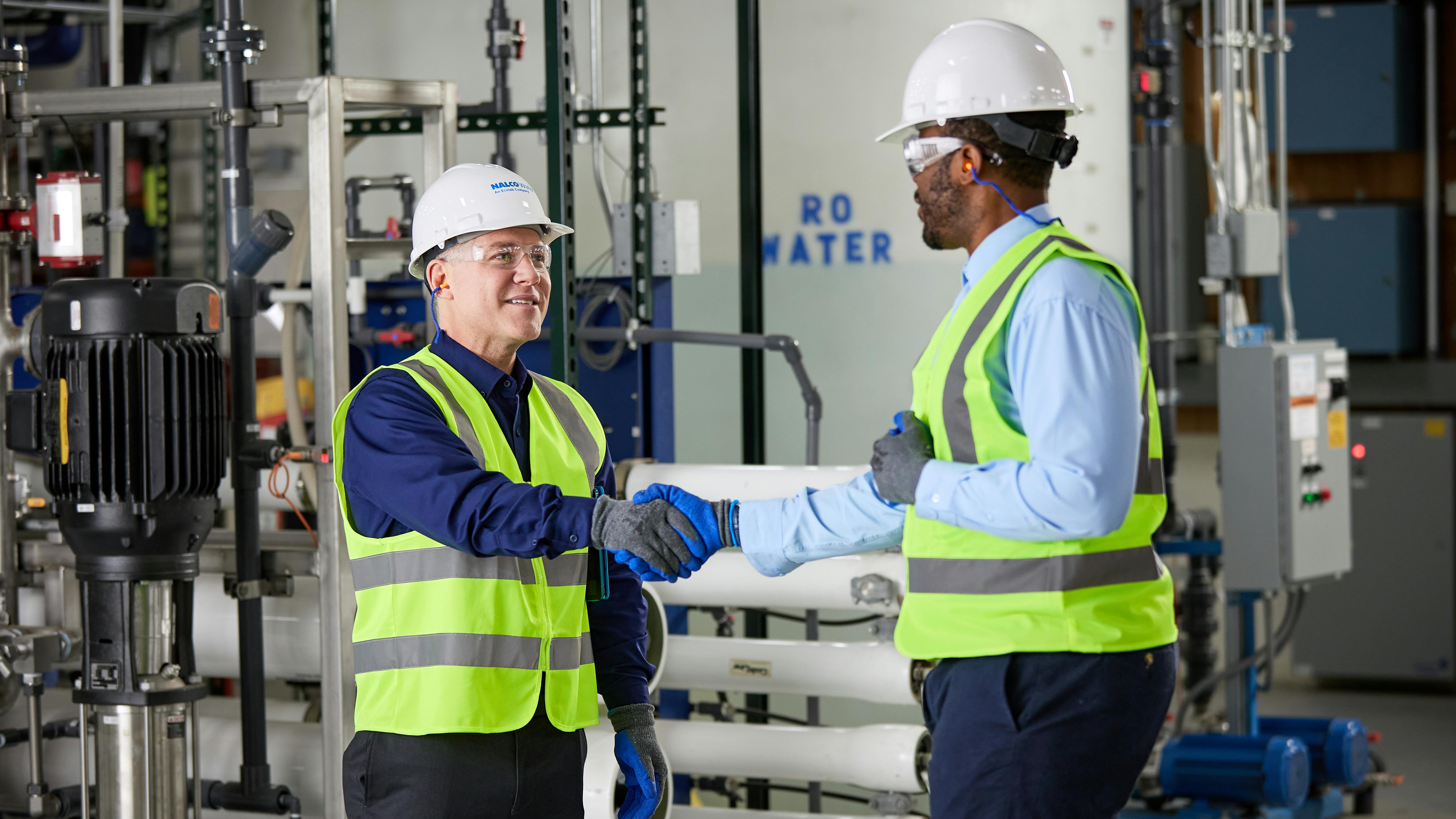 An Ecolab associate speaks with a colleague about water treatment in an industrial facility.